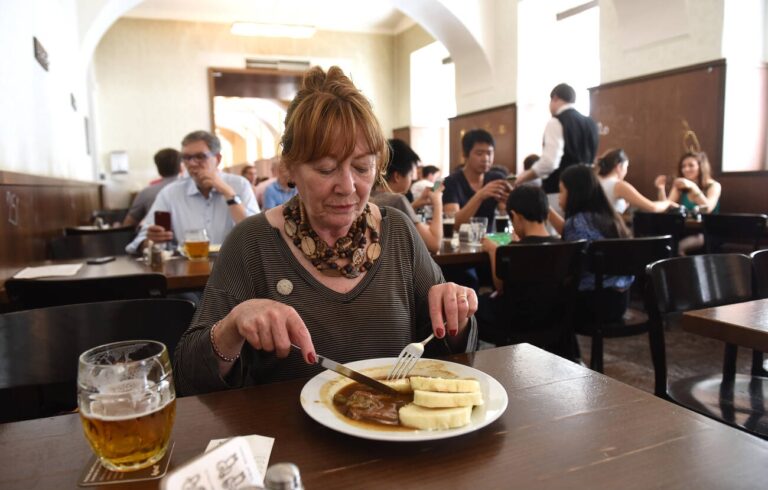 Woman with glass of traditional beer and classic Czech food at Lokal Dlouhaaa beer pub restaurant in Prague, Czech Republic